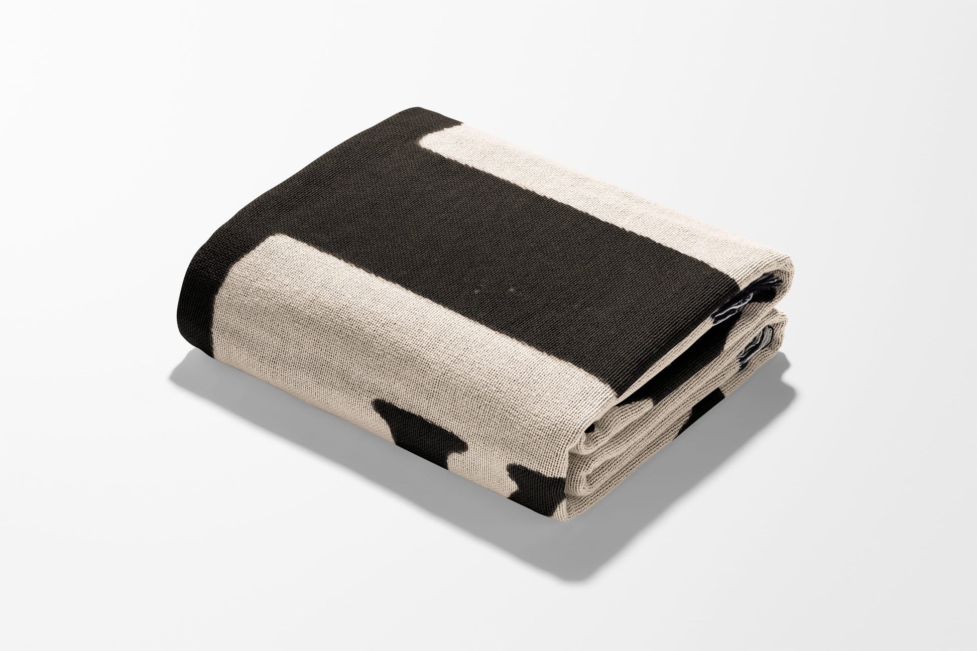Folded blanket with beige and black stripe pattern.