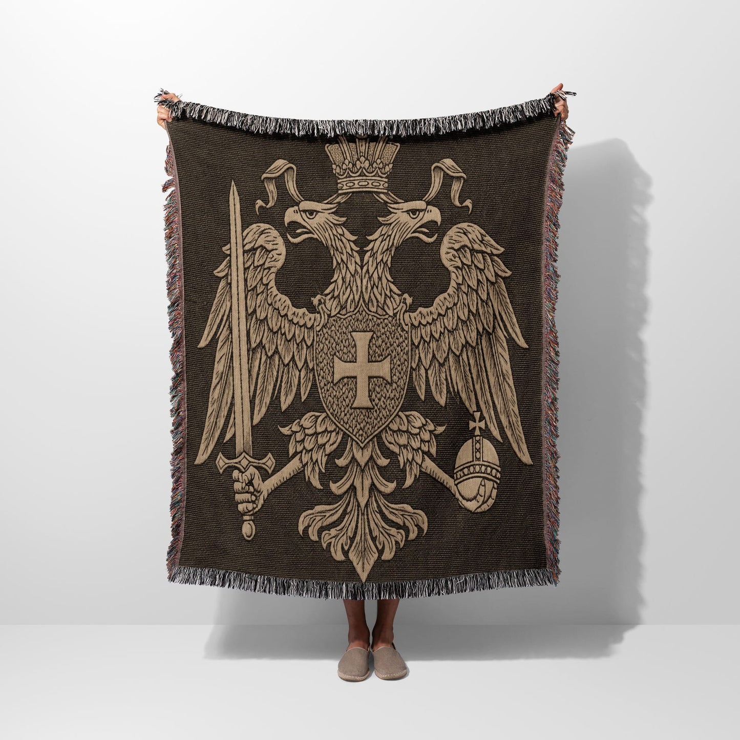 Double-headed eagle crest on a brown fringed throw blanket.