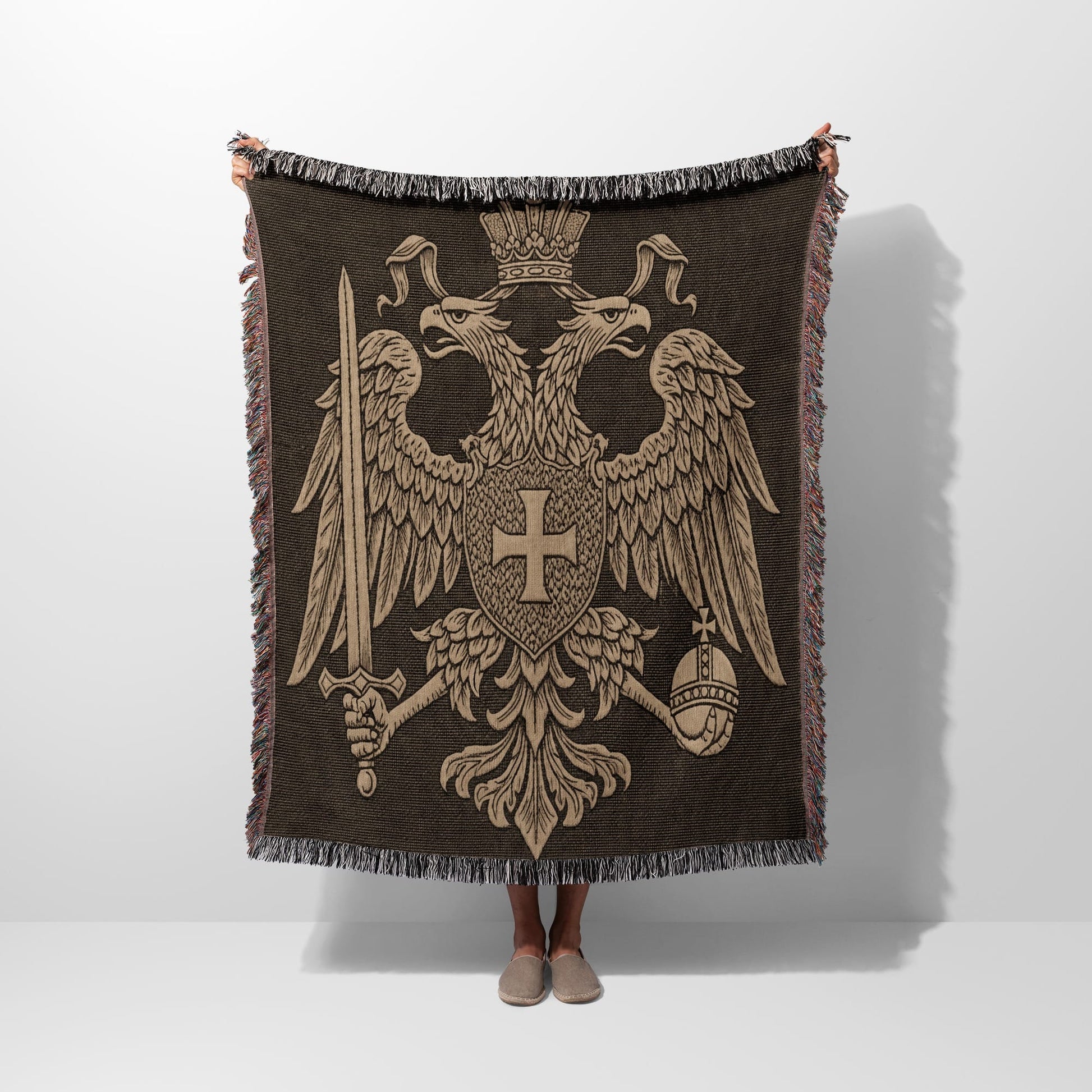Double-headed eagle crest on a brown fringed throw blanket.