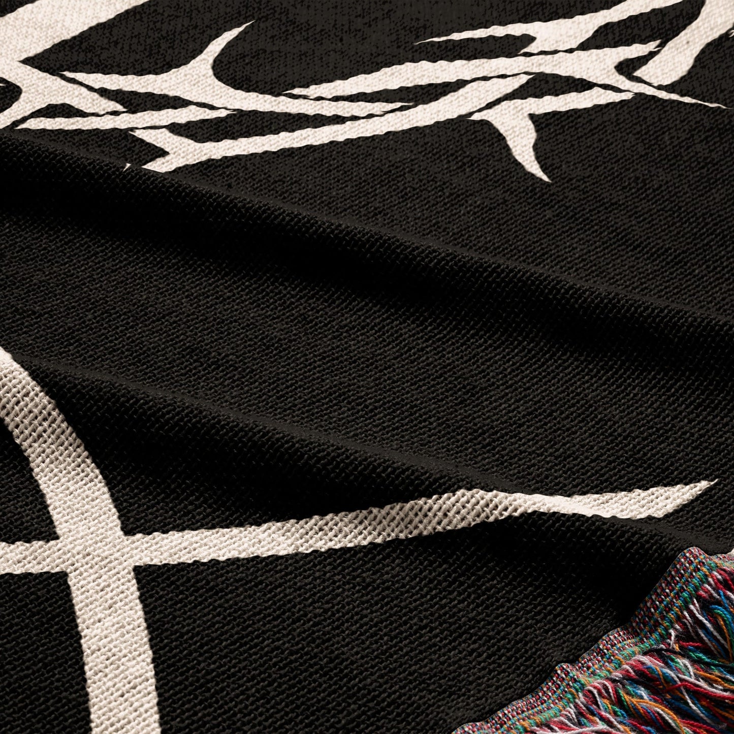 Black fabric with white tribal-like pattern and fringed edge.