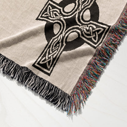 Beige throw blanket with black Celtic knot design and fringed edges.
