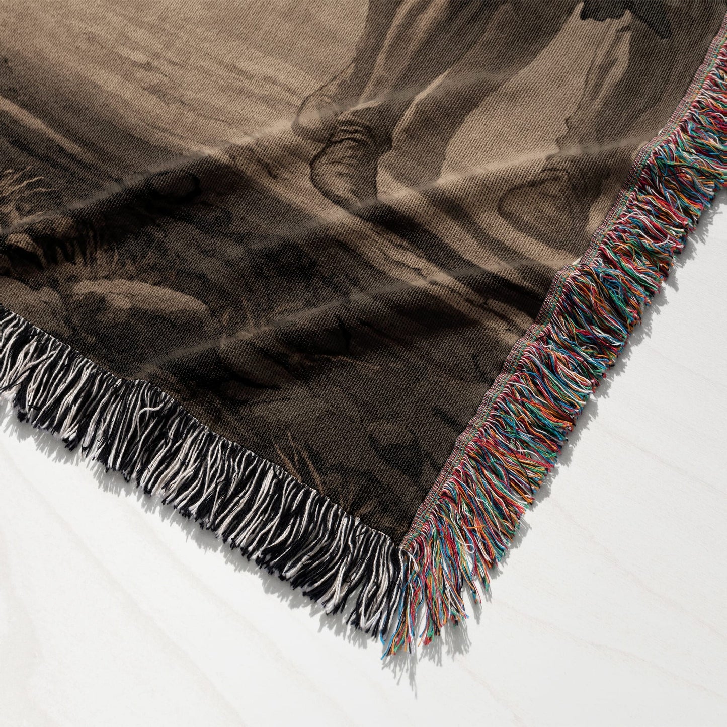 Woven throw blanket with fringed edges, featuring a dark abstract pattern.