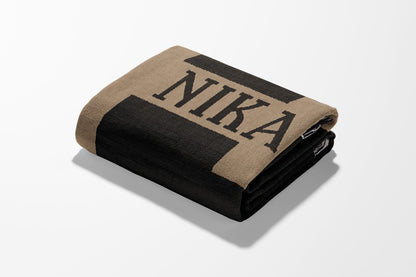Black and tan folded blanket with "NIKA" text on it.
