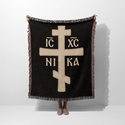 Black woven throw blanket with a large cream-colored Byzantine cross and text IC XC NIKA.