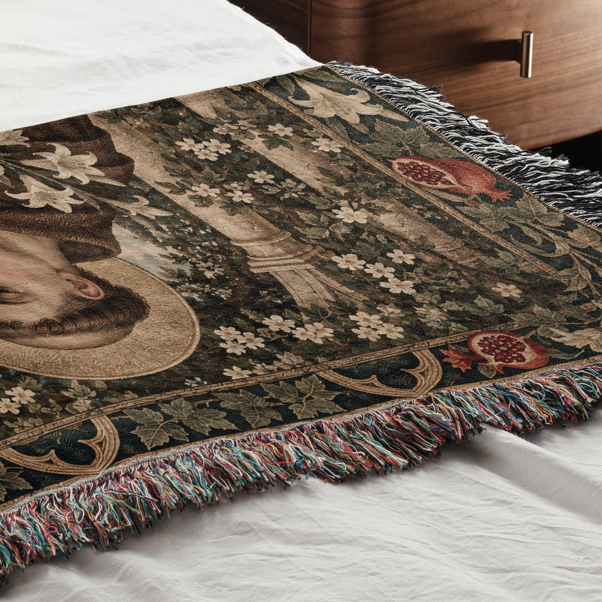 Woven throw blanket with a Renaissance art design, draped across a white bed.
