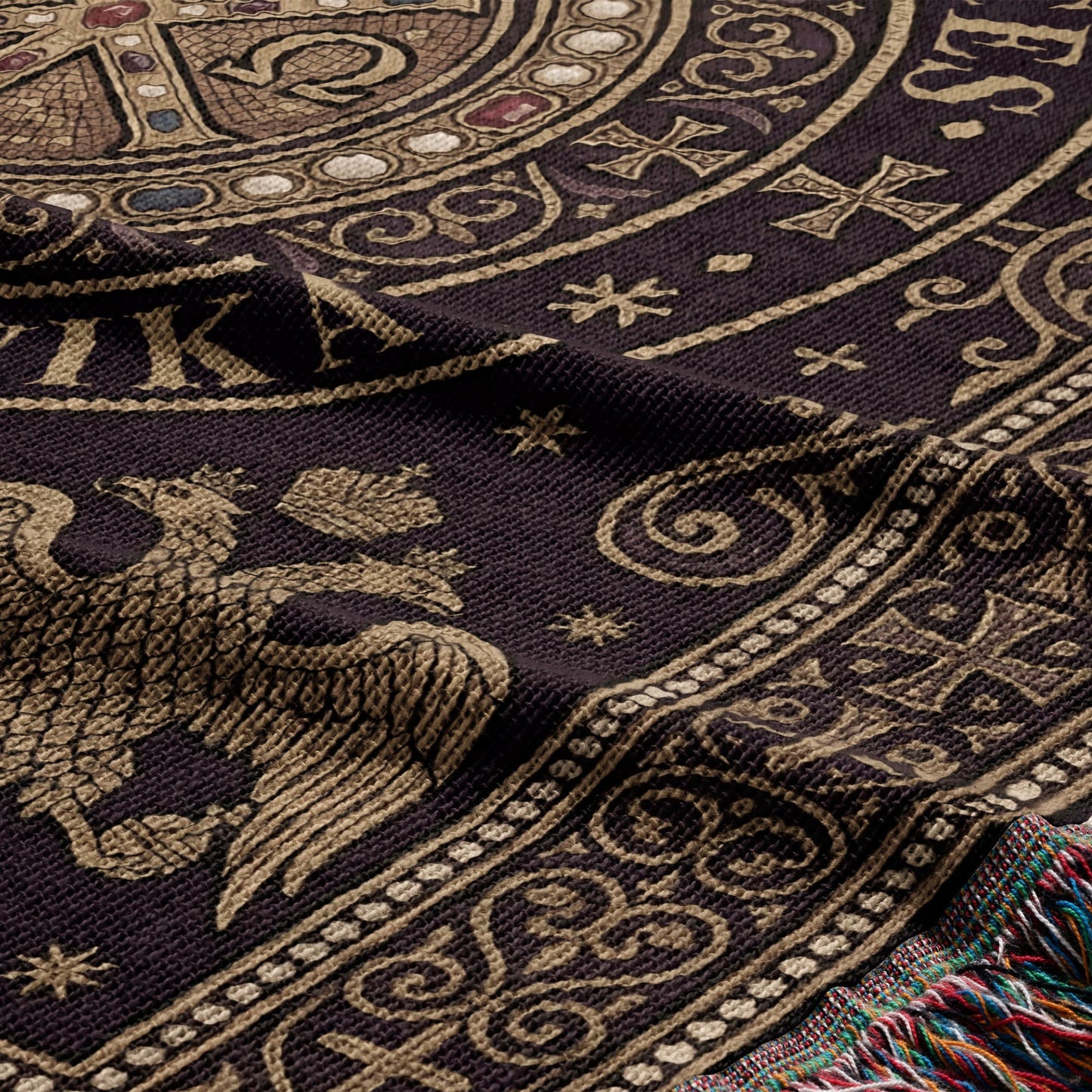 Close-up of a dark woven throw blanket with a gold eagle and ornate patterns.