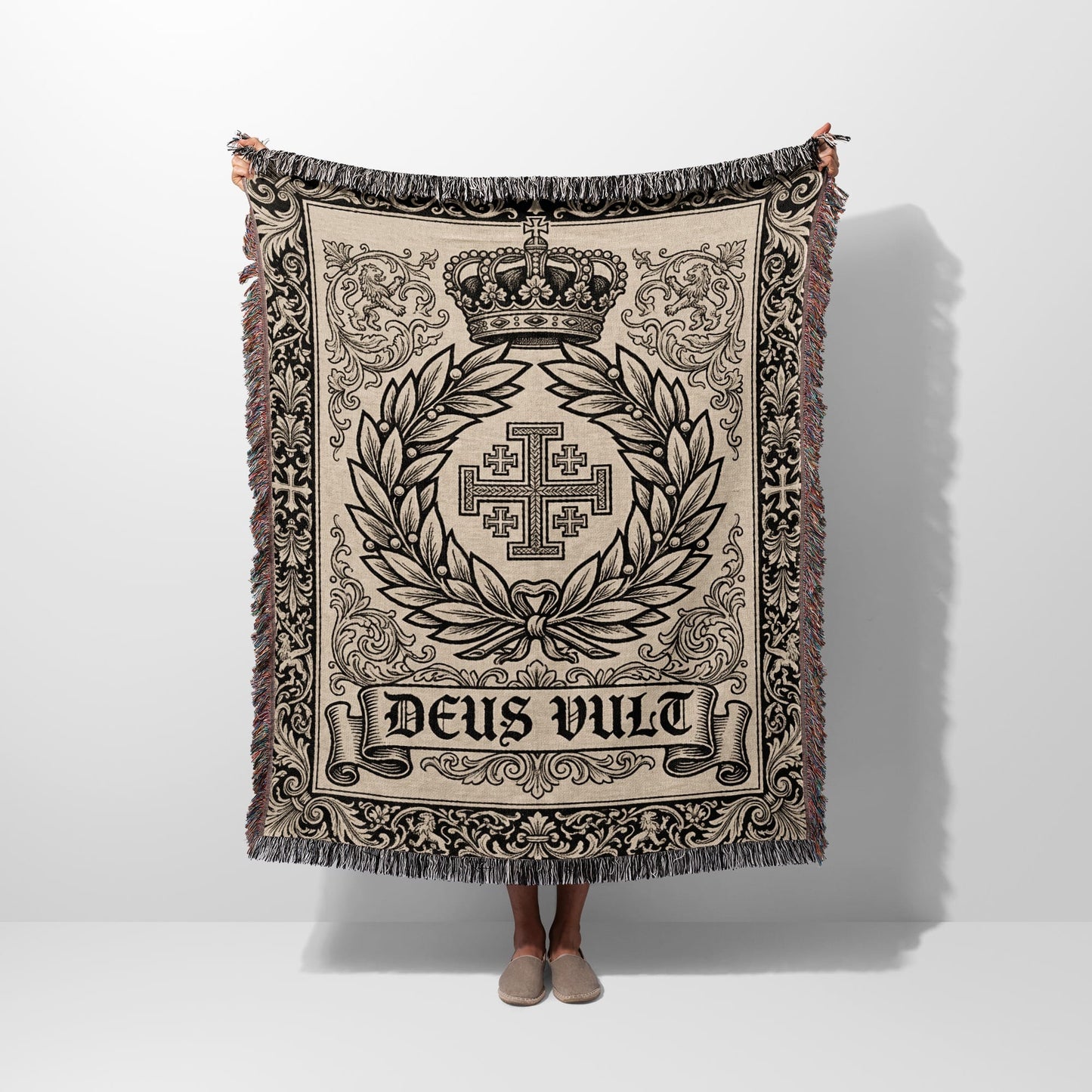 Woven blanket with a crown, cross, and "DEUS VULT" text on a neutral background.