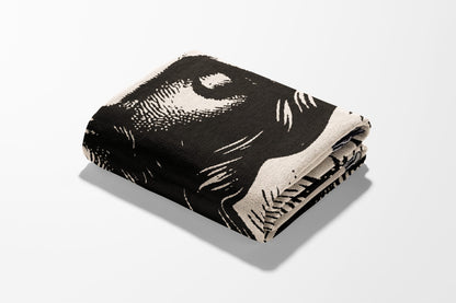 Folded blanket with a black and white abstract face design.