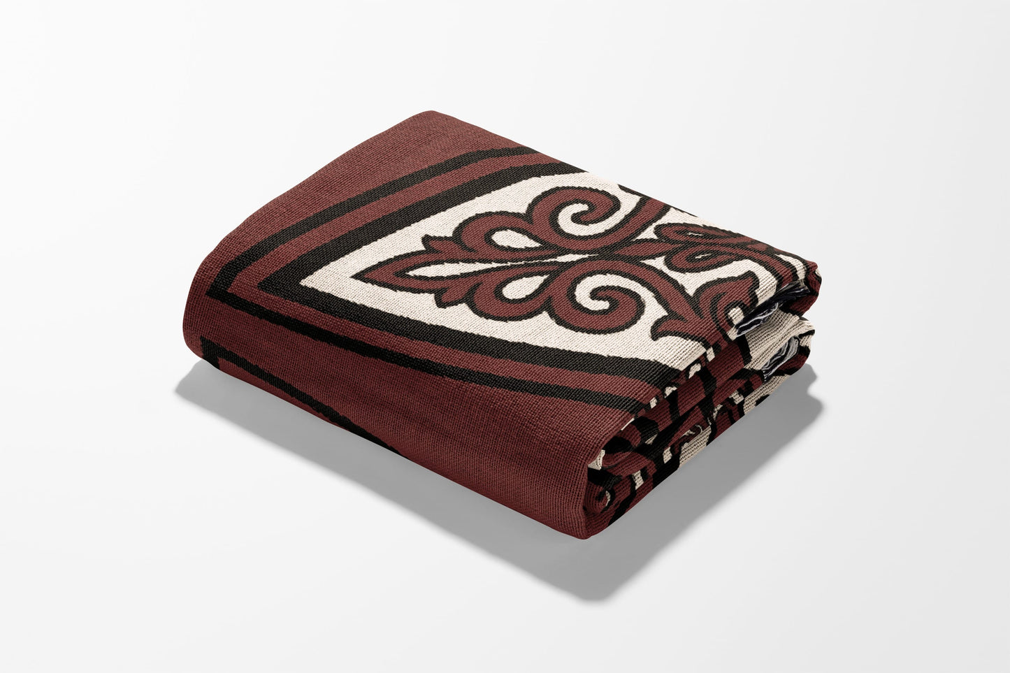 Folded maroon blanket with intricate cream and black swirl pattern.