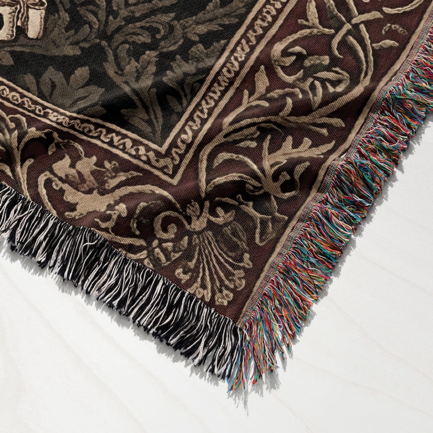 Woven throw blanket with dark brown and tan floral pattern and fringed edges.