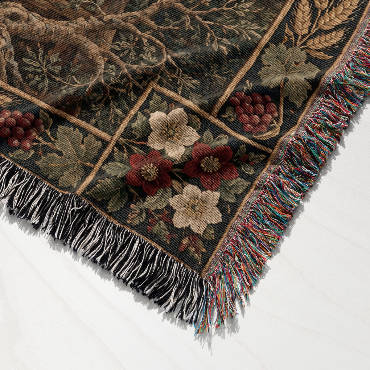 A woven throw blanket featuring a botanical grid pattern with flowers, grapes, and multicolored fringed edges.