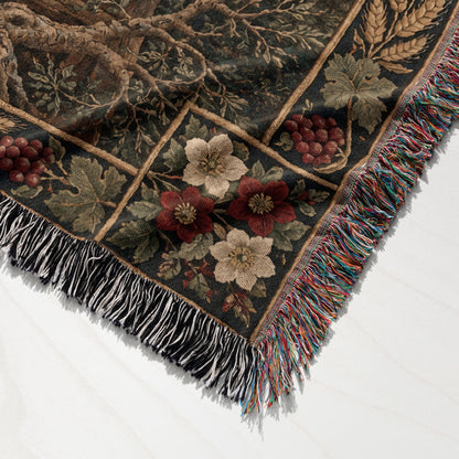 A woven throw blanket featuring a botanical grid pattern with flowers, grapes, and multicolored fringed edges.
