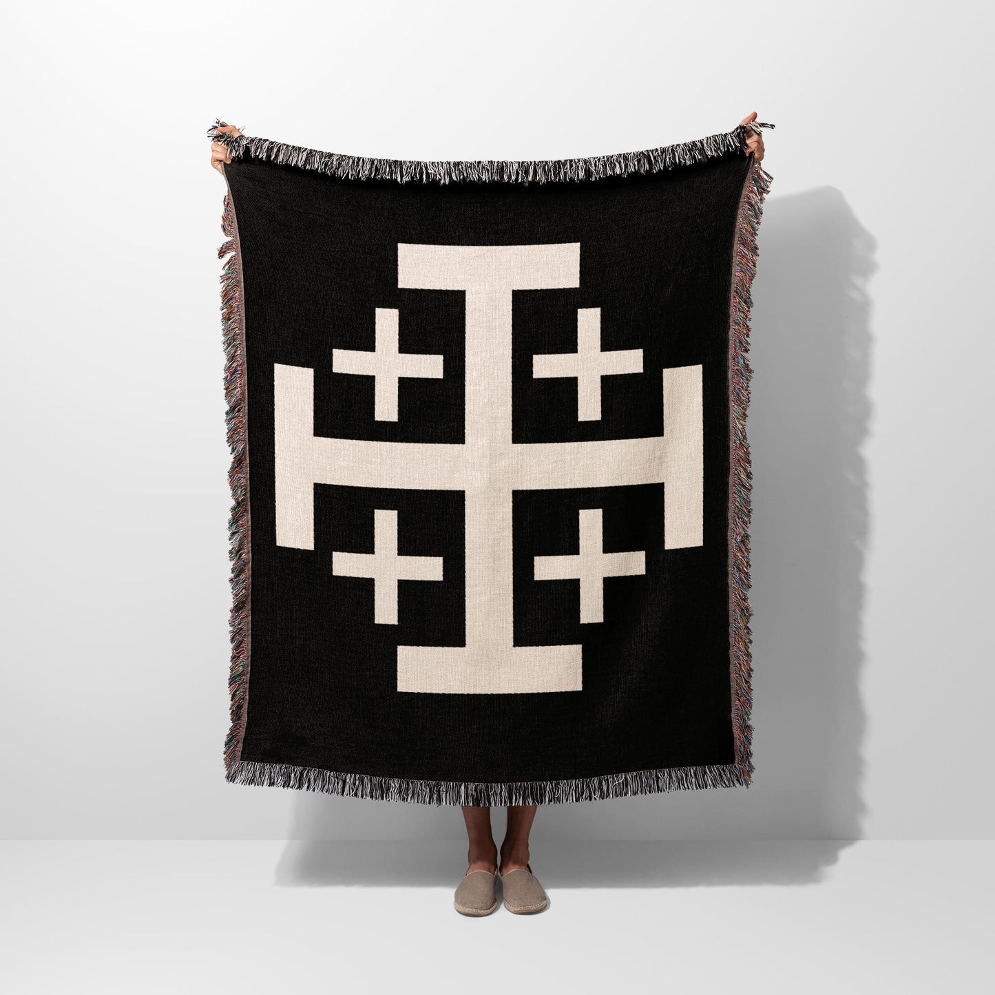 Black throw blanket with a large cream geometric cross pattern.