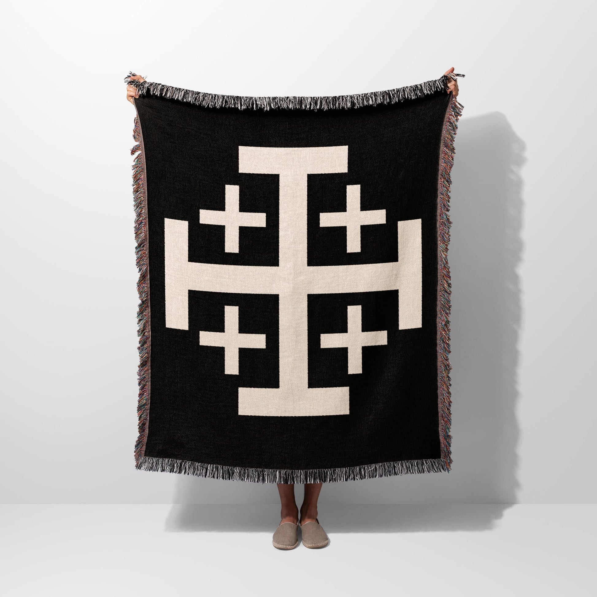 Black throw blanket with a large cream geometric cross pattern.
