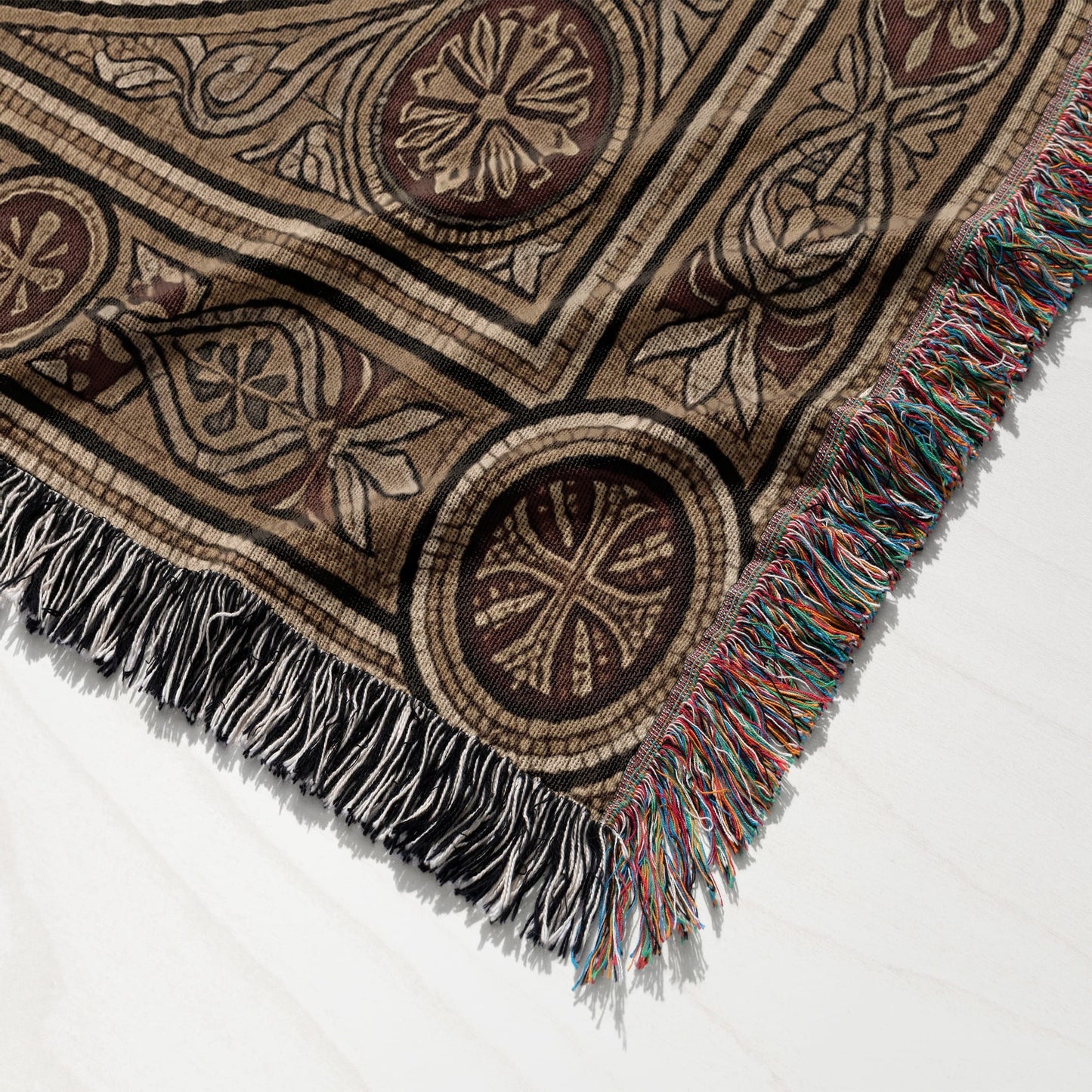 Woven blanket with geometric and floral patterns, and fringed edges.