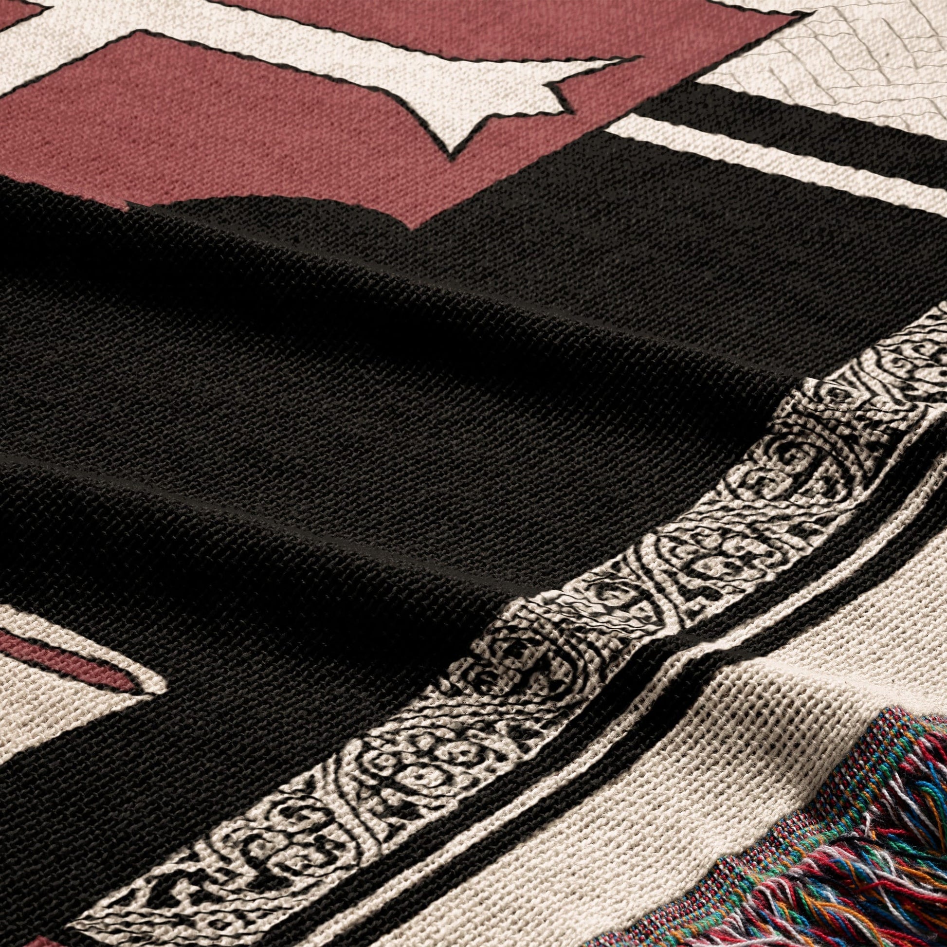 Black and white patterned throw blanket with tasseled edge and maroon design.