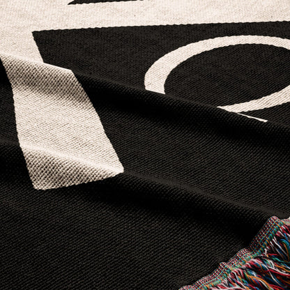 Black knit throw with white lettering and fringed edge detail.