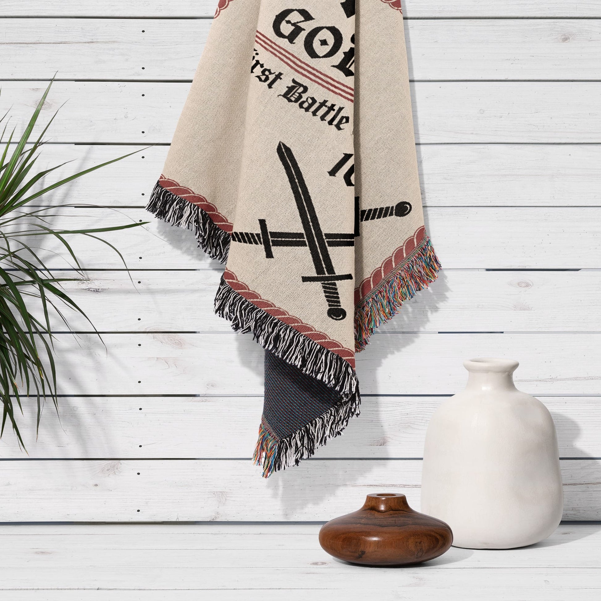 Woven throw blanket with crossed swords and "First Battle" text.
