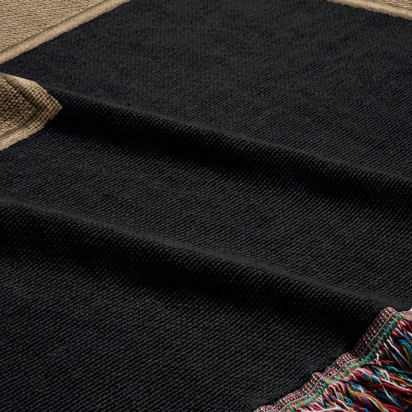 Black woven throw blanket with fringed colorful edges.