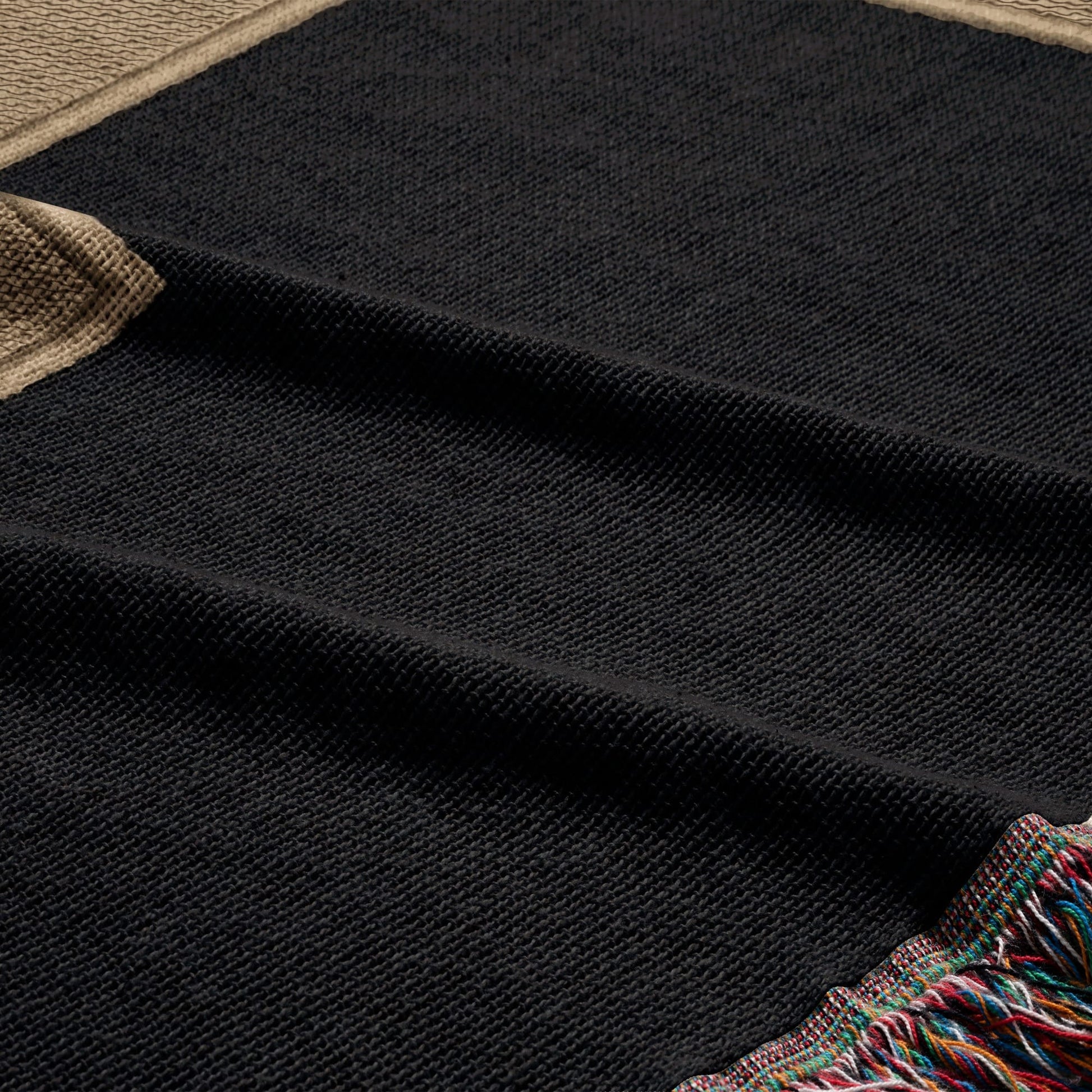 Black woven throw blanket with fringed colorful edges.