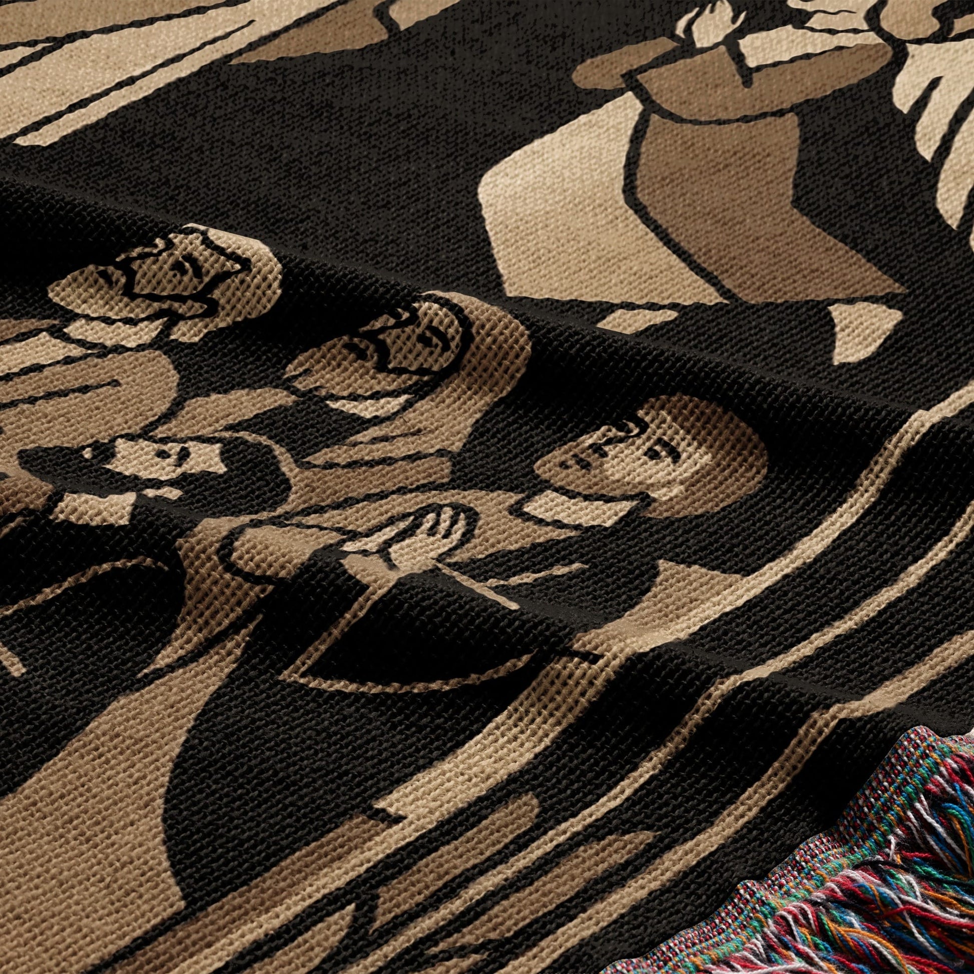 Woven blanket with religious figures in tan and black, fringed edge.