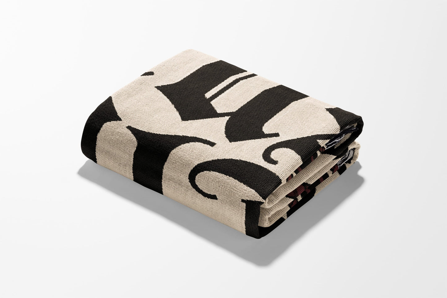 Folded blanket with large black gothic "H" pattern on cream background.