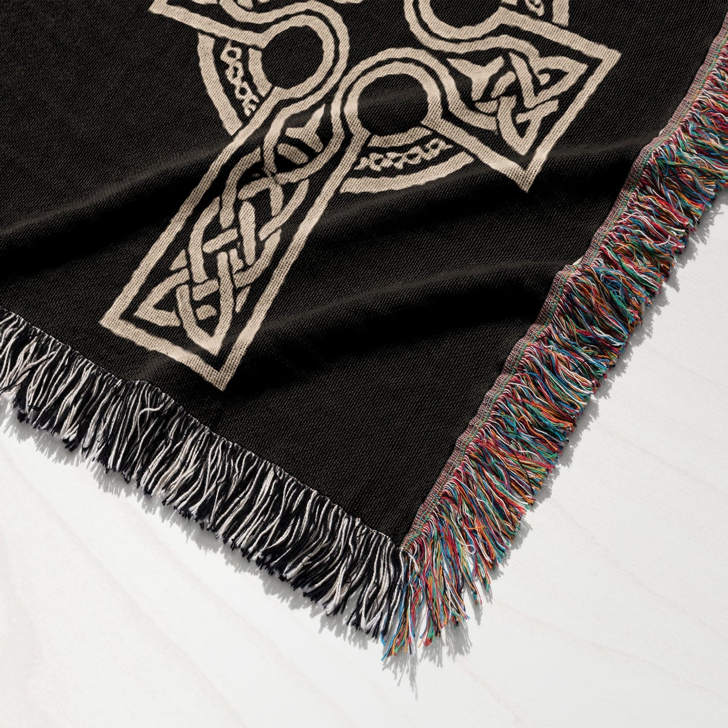 Black woven throw blanket with a beige Celtic knot design and fringed edges.