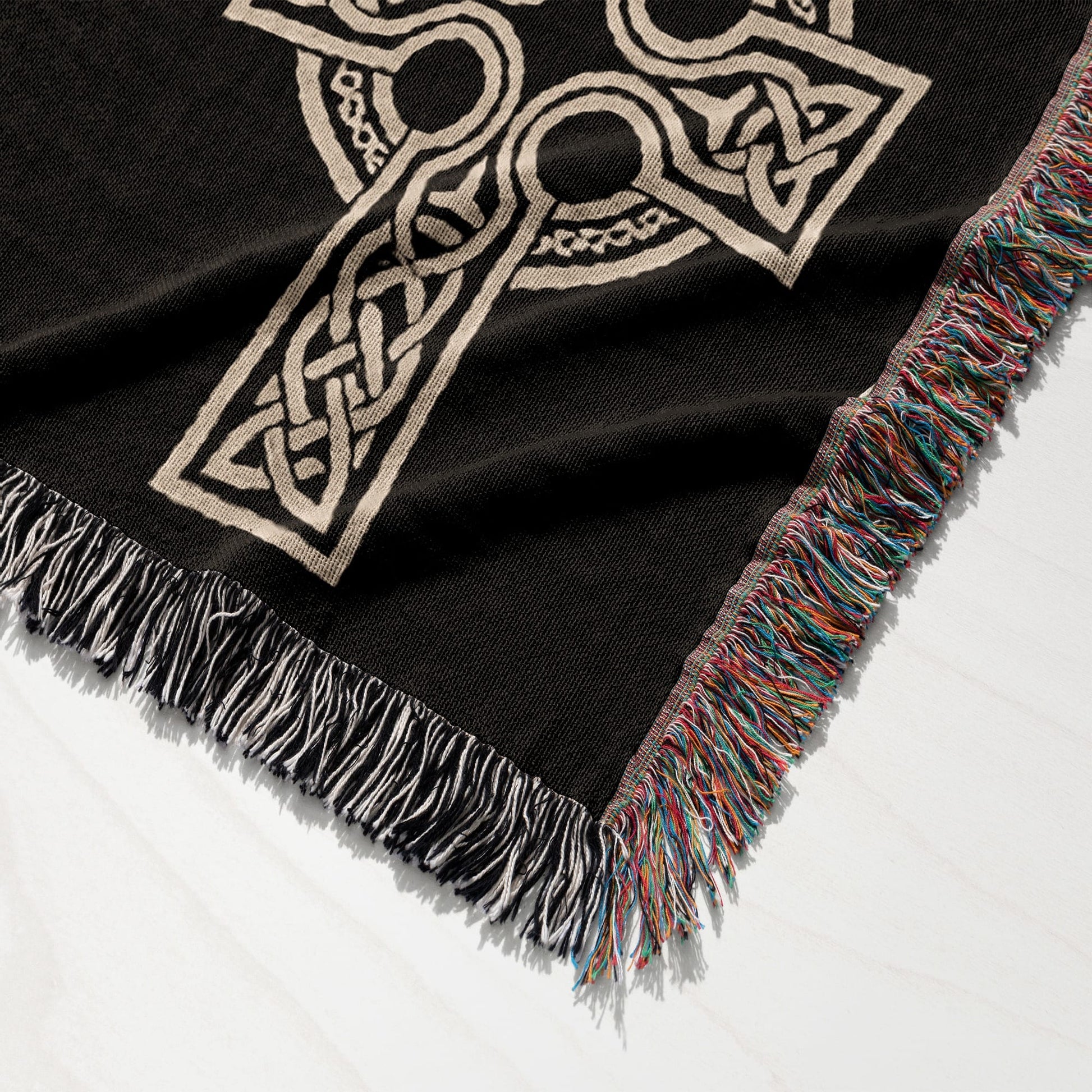 Black woven throw blanket with a beige Celtic knot design and fringed edges.