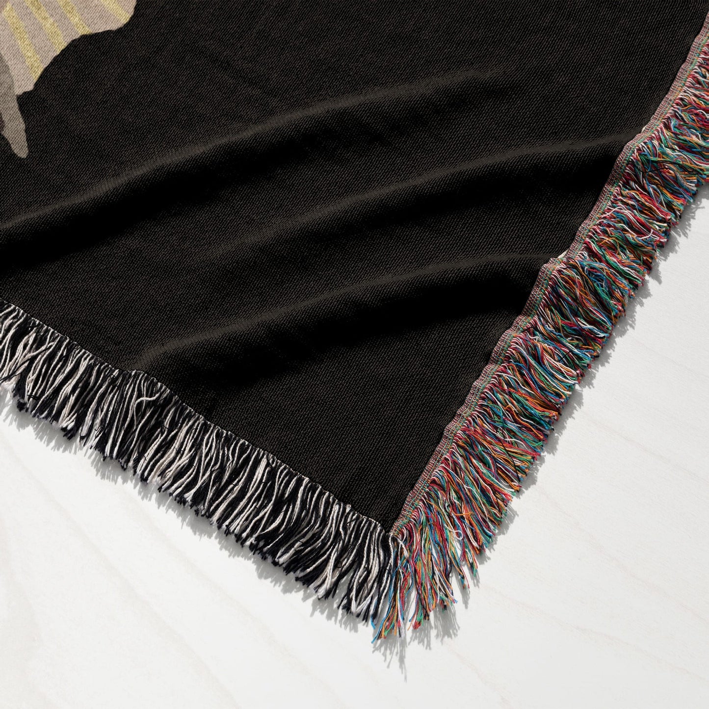 Black woven throw blanket with fringed edge in multiple colors.