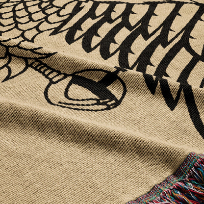 Tan throw blanket with black dragon motif and fringed edge.