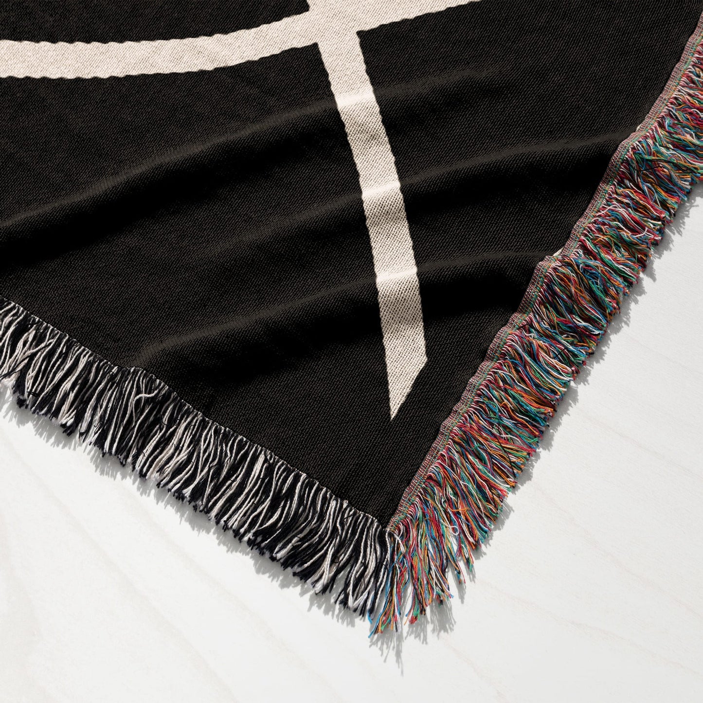 Black blanket with white geometric pattern and multicolored fringe.