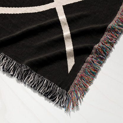 Black blanket with white geometric pattern and multicolored fringe.