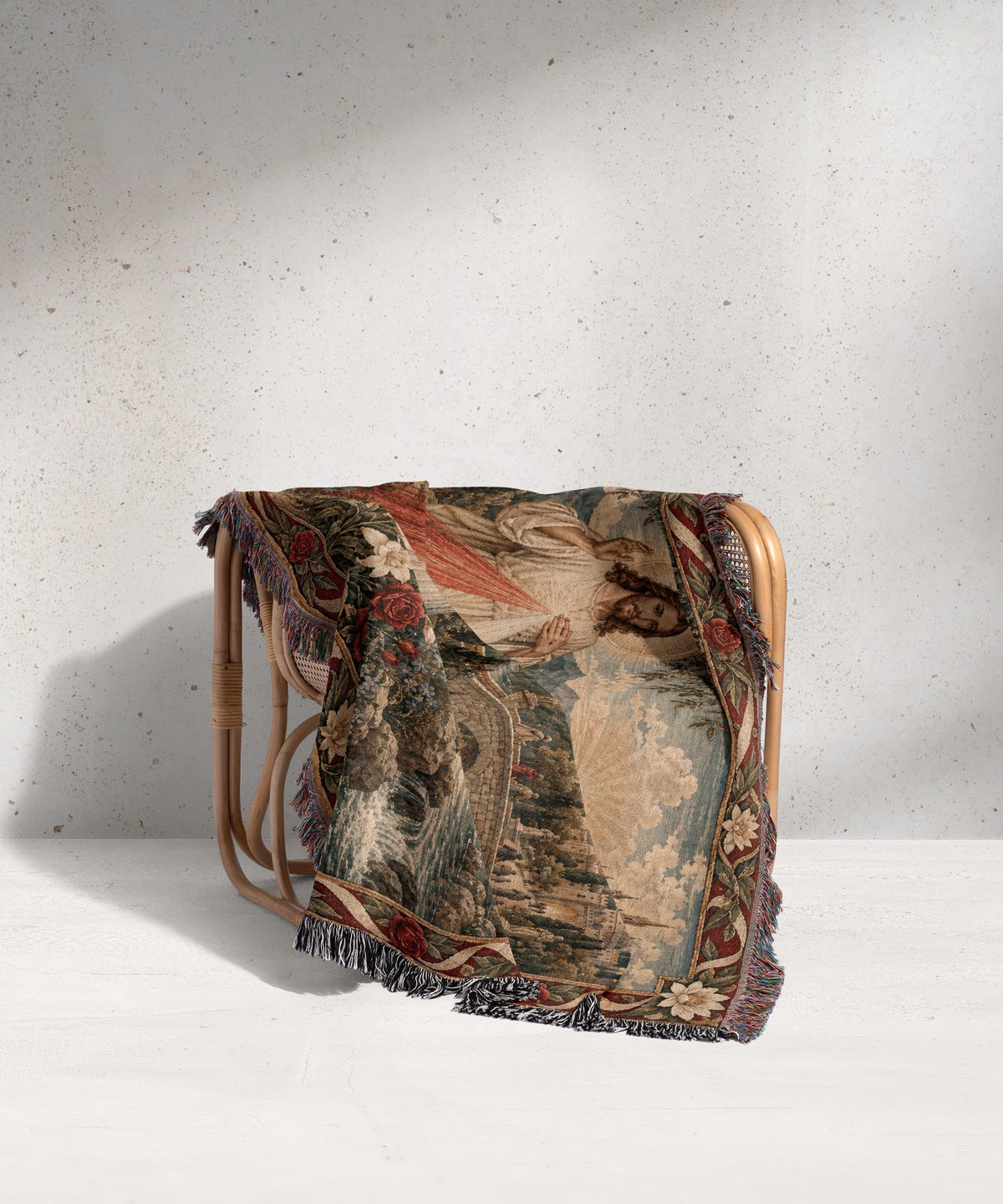 A woven tapestry blanket featuring the Divine Mercy image draped over a light wooden chair.