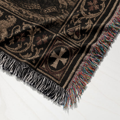 Black woven throw blanket with multicolor fringe and ornate medieval-style pattern.