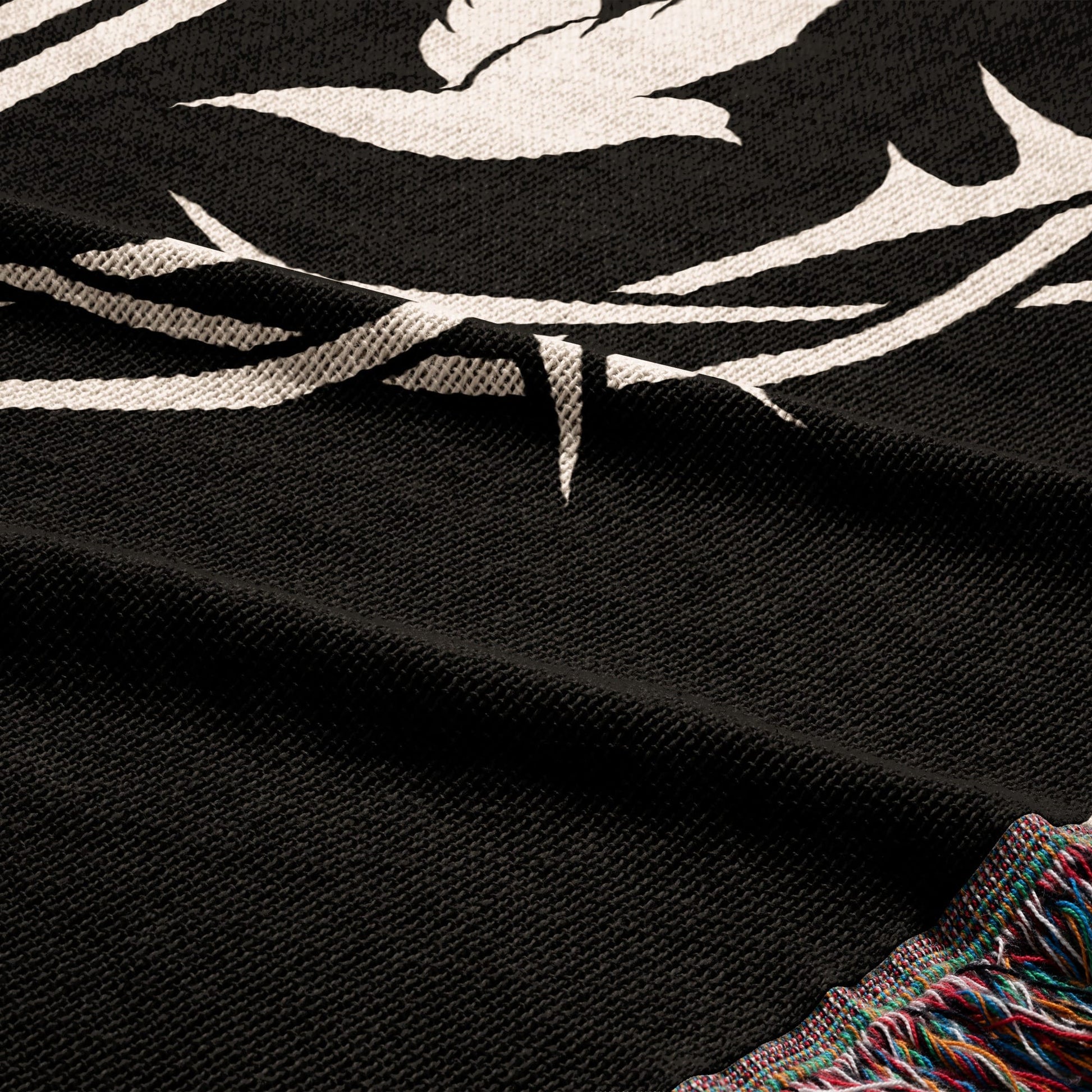 Black woven blanket with white bird and crown design, fringed edge.