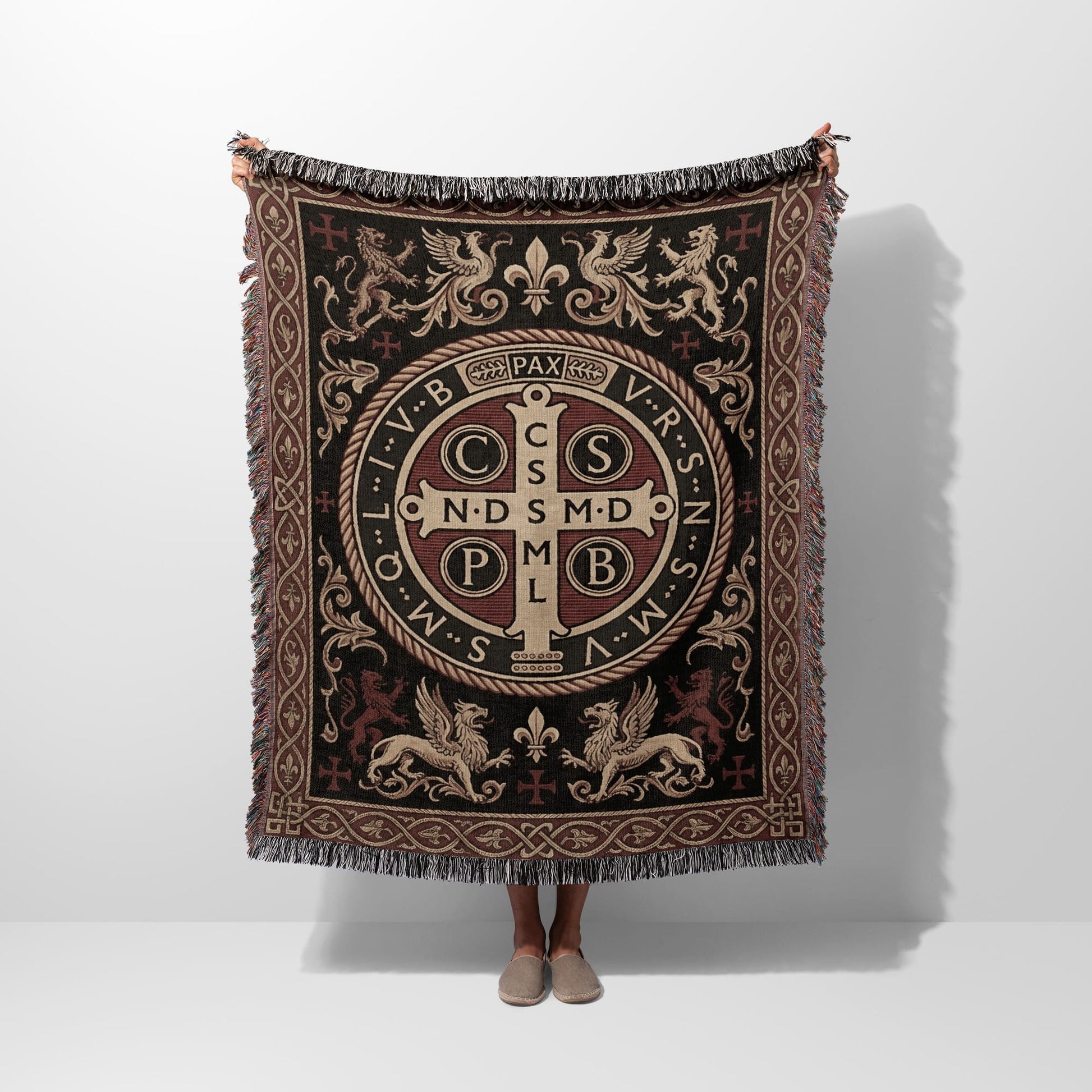Tapestry throw with St. Benedict medal design, fringe, and medieval motifs.