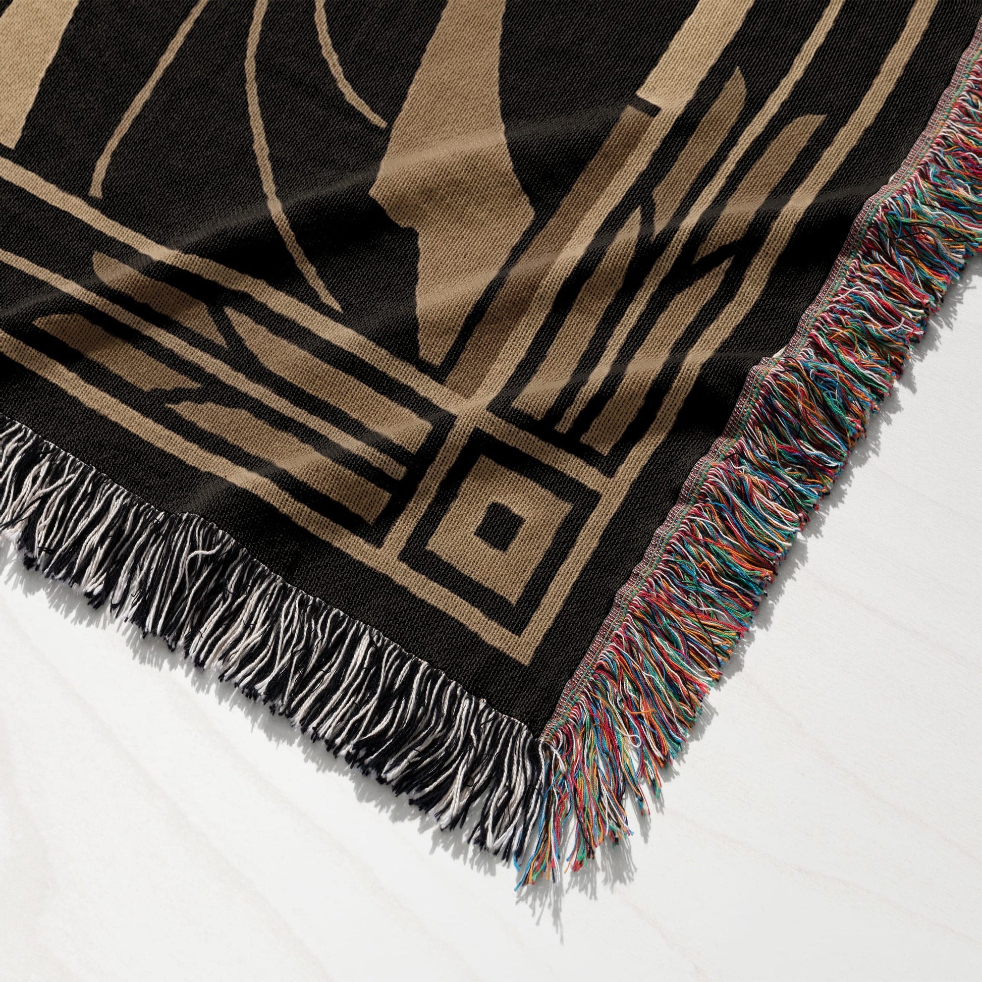 Black and tan woven throw blanket with fringed edges, featuring geometric pattern.