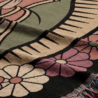 Woven blanket with floral and abstract designs in green, tan, and pink.