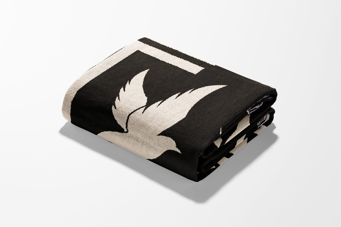Black blanket with cream bird design, folded on white surface.