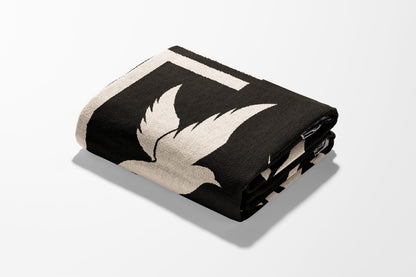 Black blanket with cream bird design, folded on white surface.