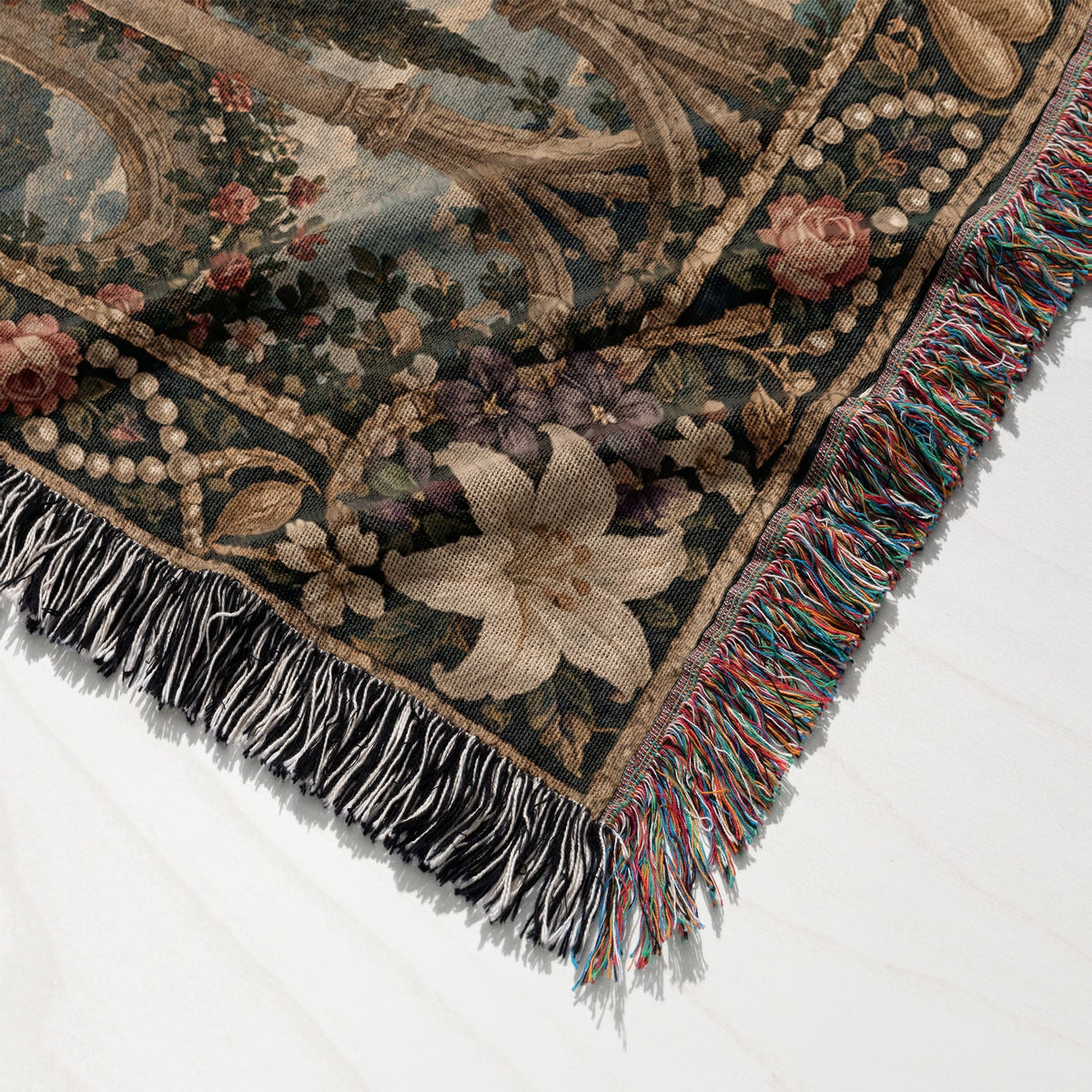 Close-up of a woven tapestry blanket featuring floral patterns and multi-colored fringed edges.