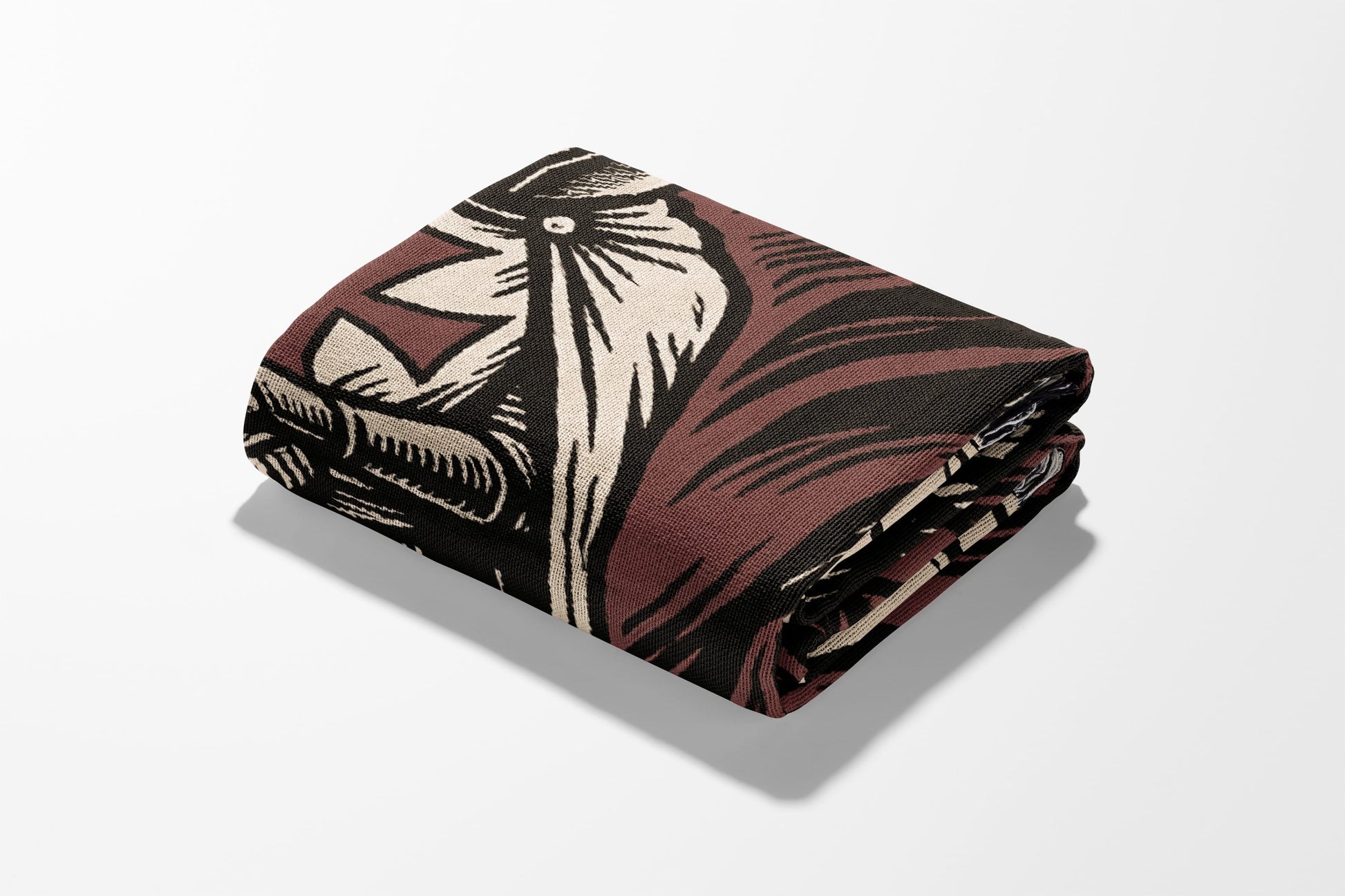 Folded blanket with a bold, graphic pattern in brown, cream, and black.