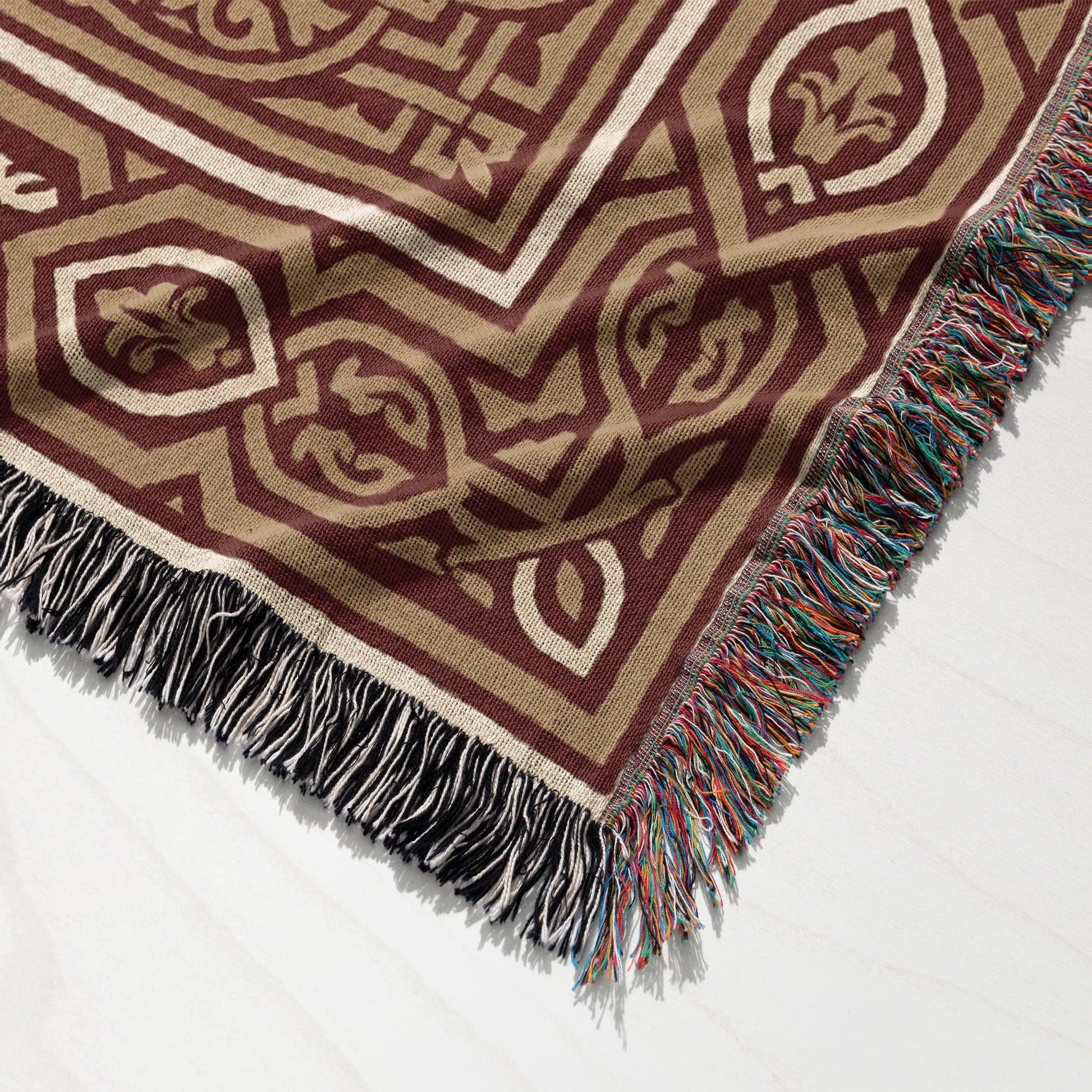 Brown and tan geometric pattern blanket with multicolored fringe.