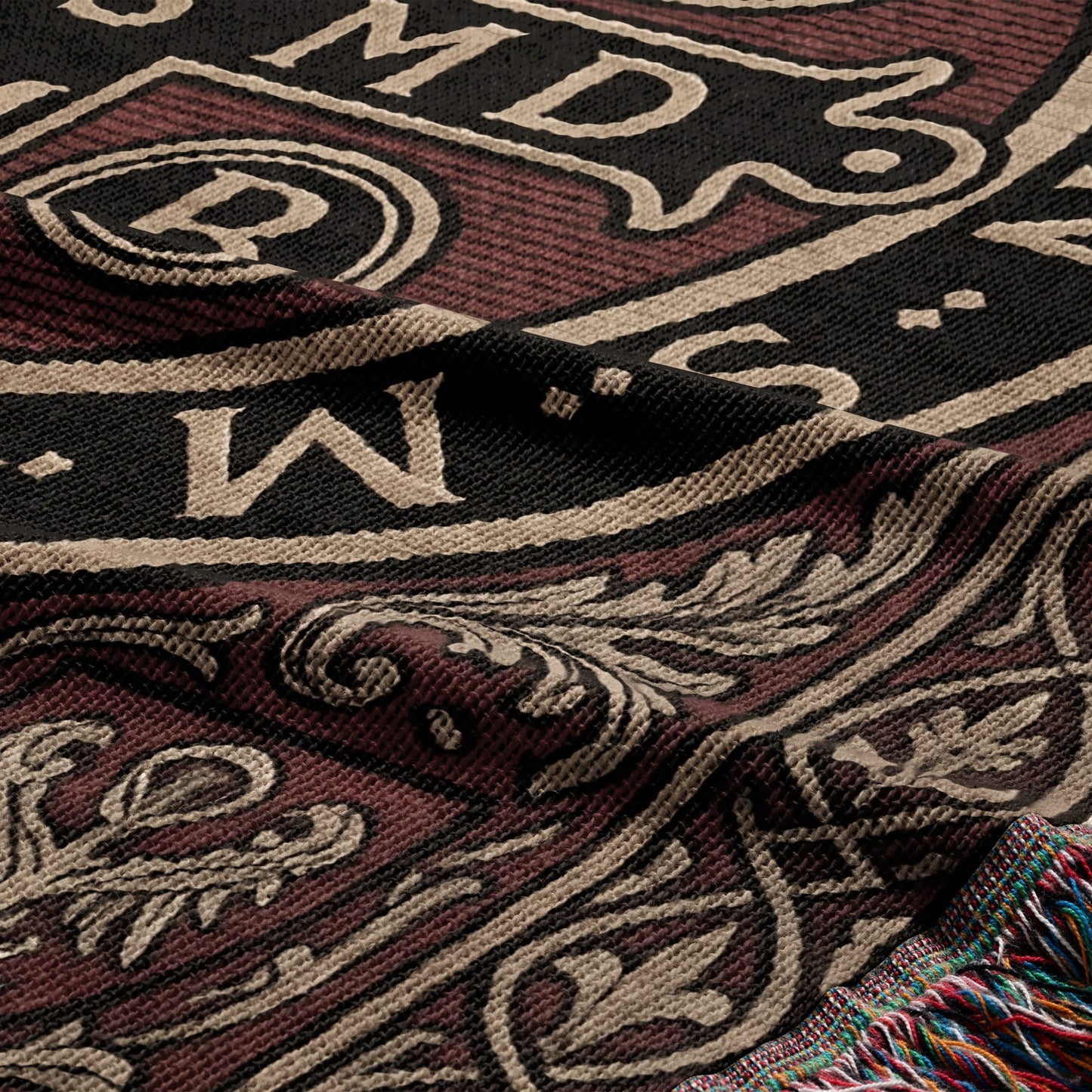 Woven blanket with "MD" and a stylized "R" in black, cream, and maroon.