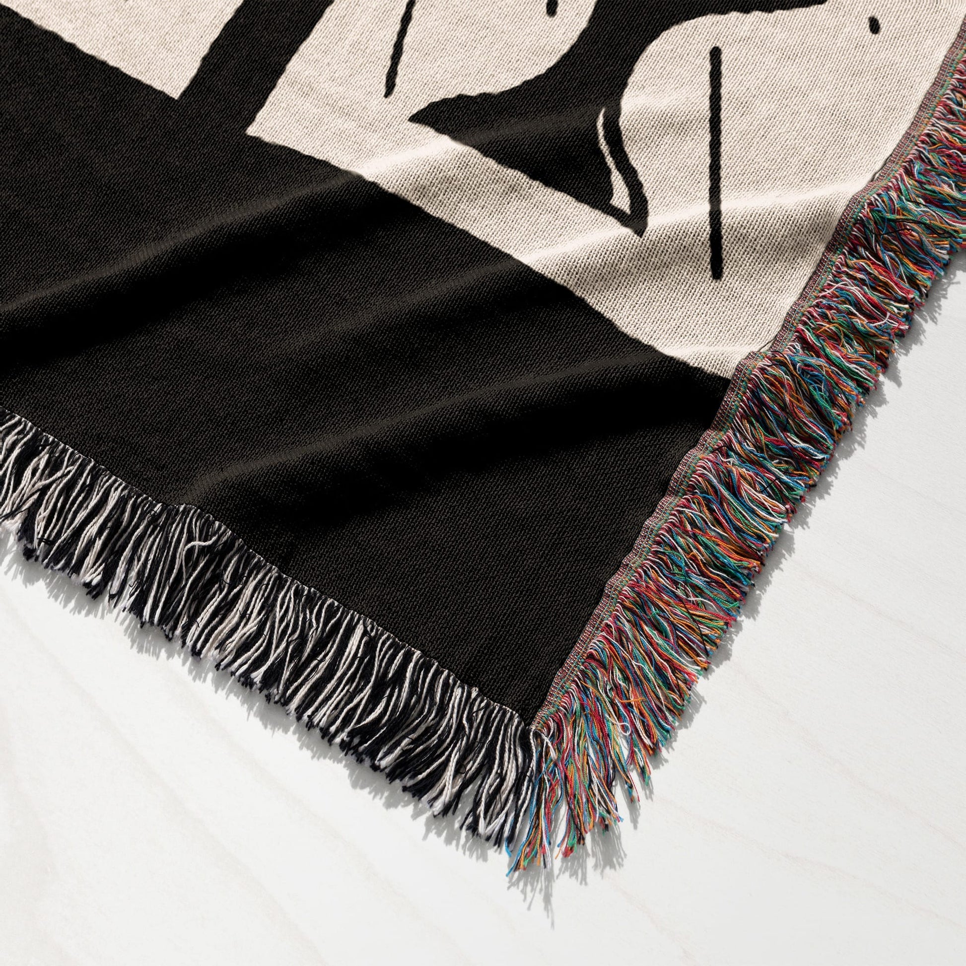 Black knit blanket with fringe, detail of woven pattern.