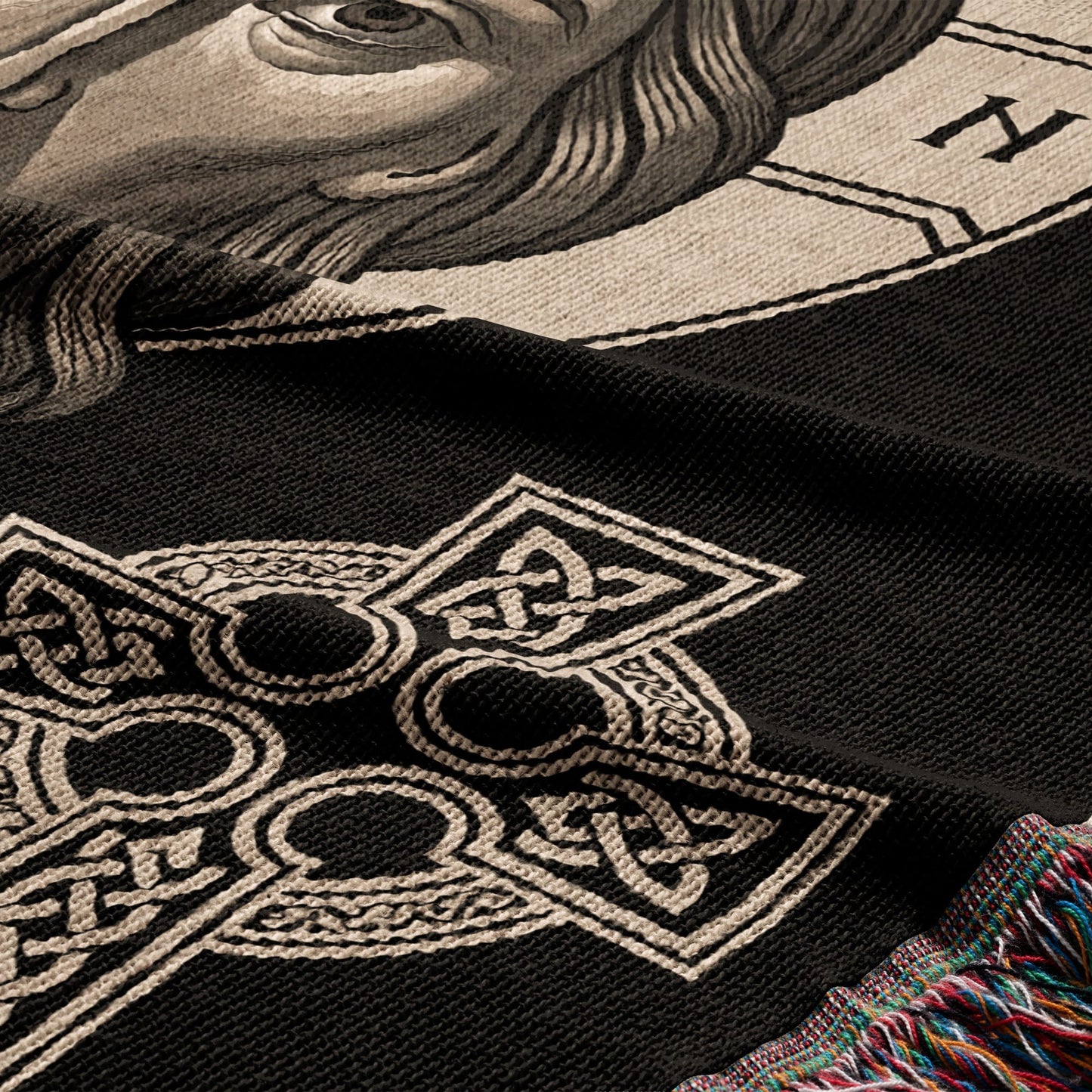 Black throw blanket with Celtic knot cross and partial portrait detail.