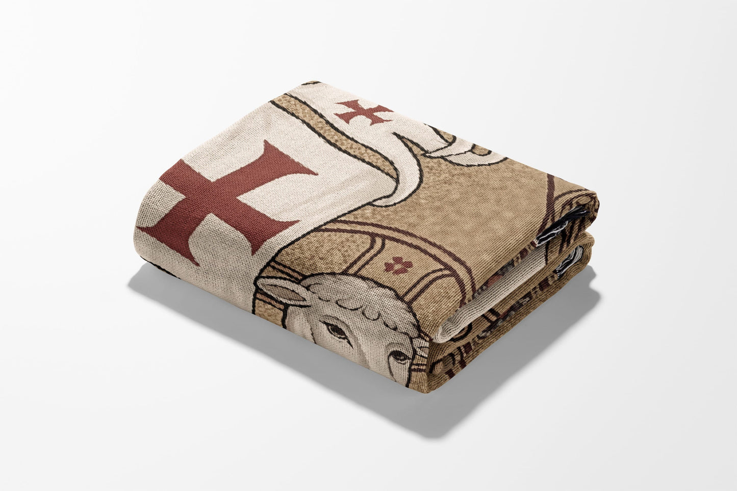 Folded blanket with tan, red cross, and lamb design.