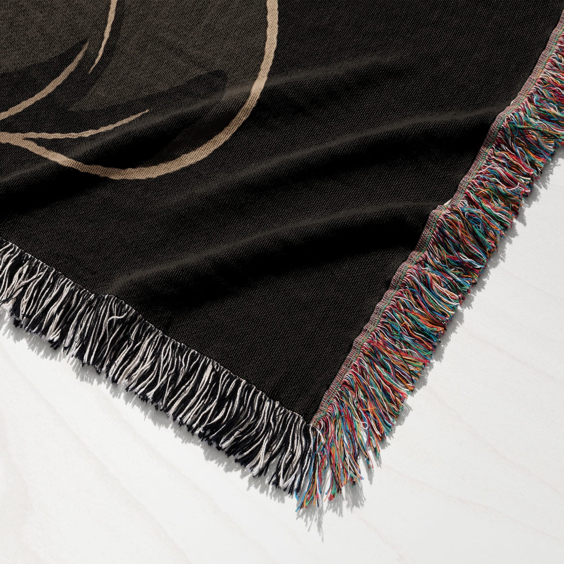 Black woven throw blanket with colorful fringe detail and a subtle pattern.