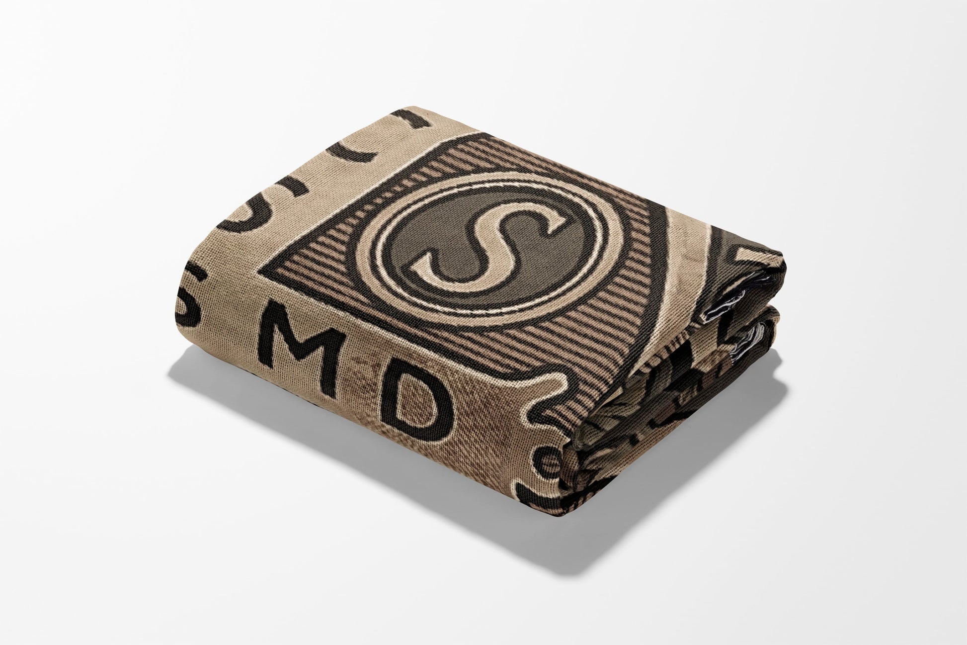 Folded blanket with a repeating pattern of letters and circles on a tan background.