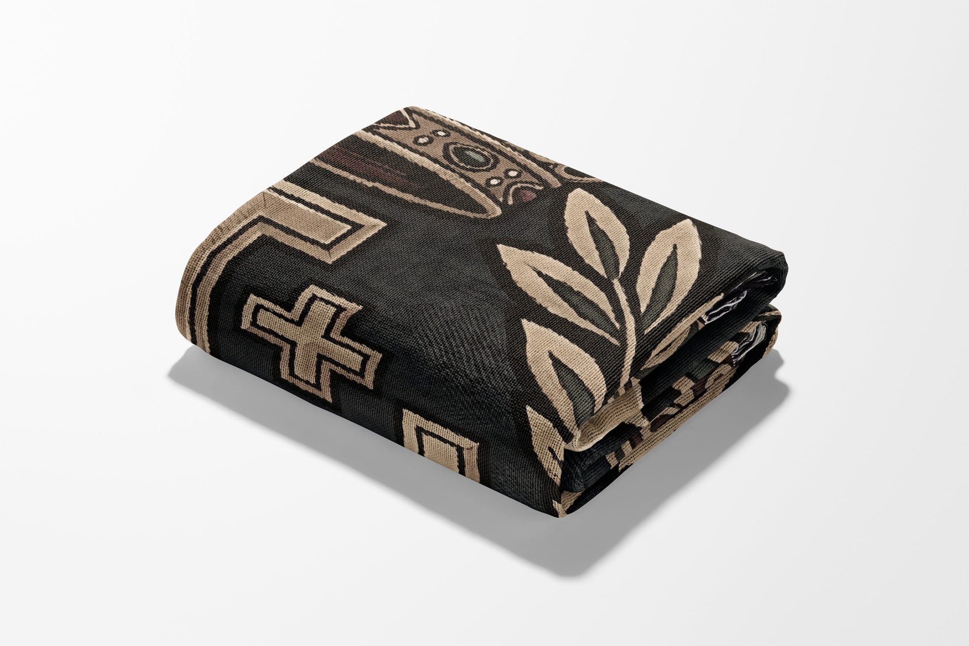 Folded dark blanket with geometric and leaf-like patterns in beige and brown.